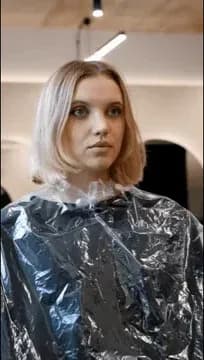 Klientka w przezroczystej pelerynie fryzjerskiej w salonie CutCut