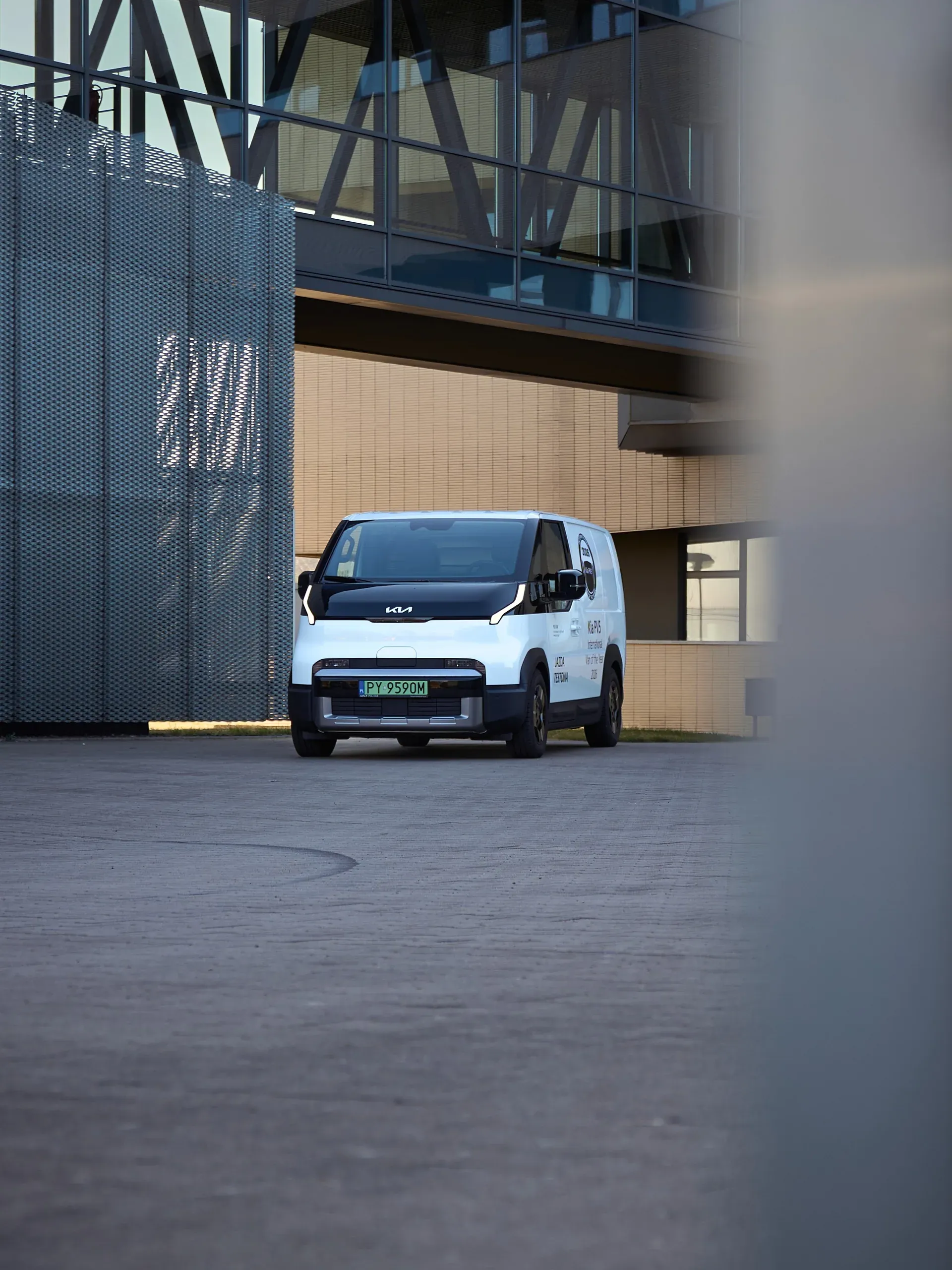 Kia PV5 w oddali, w kadrze otoczonym elementami architektury